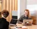 deux étudiants souriant devant leur ordinateur